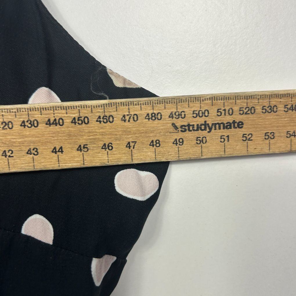 Black fabric with white polka dots detail view with measuring tape