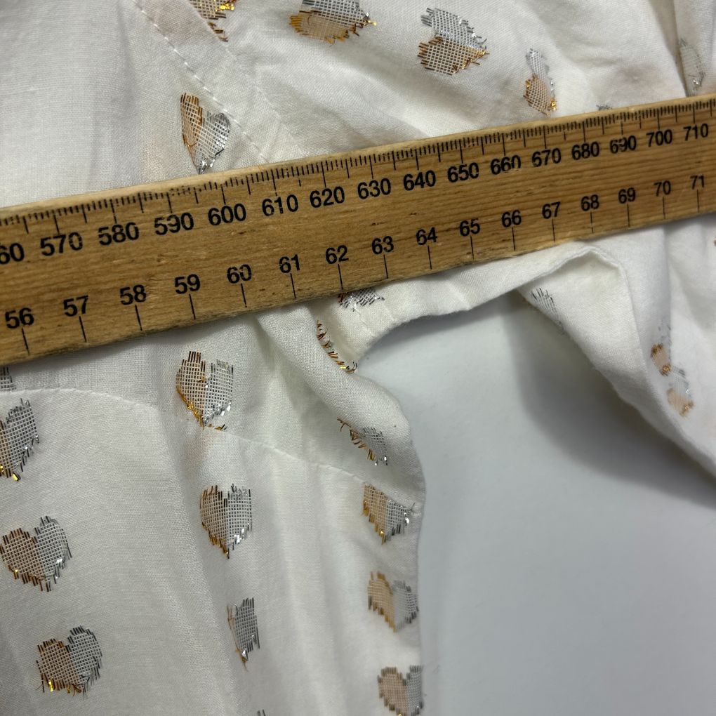 White fabric with heart pattern detail view with measuring tape
