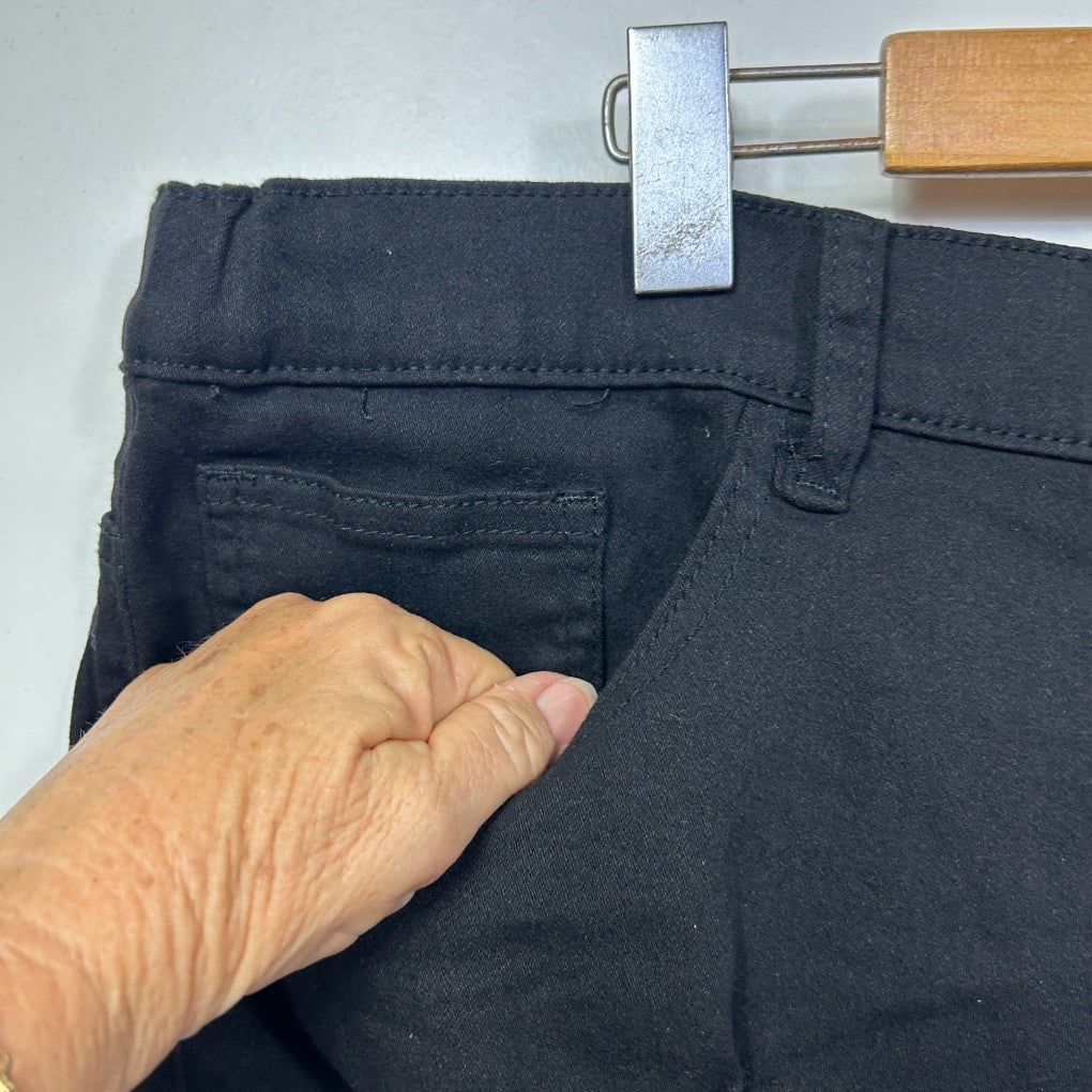Black jeans front detail view with hand pointing to pocket