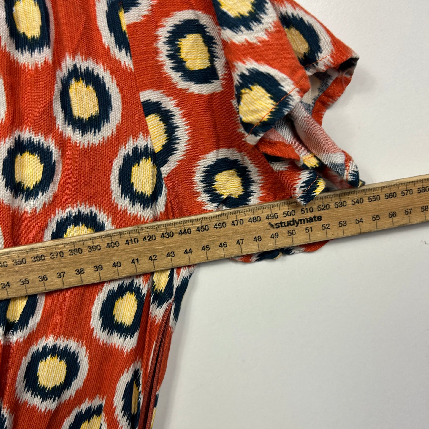 Red ikat pattern fabric detail view with measuring tape
