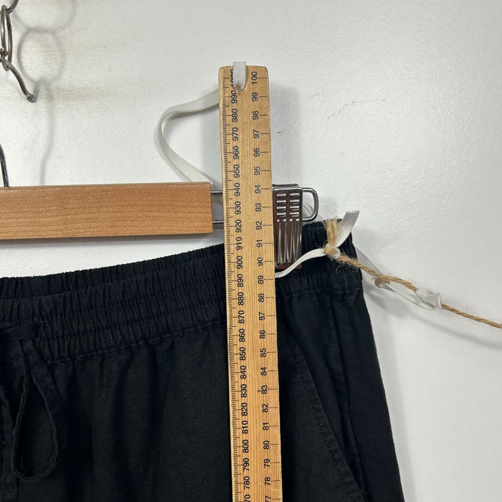 Black pants waistband detail view with measuring tape
