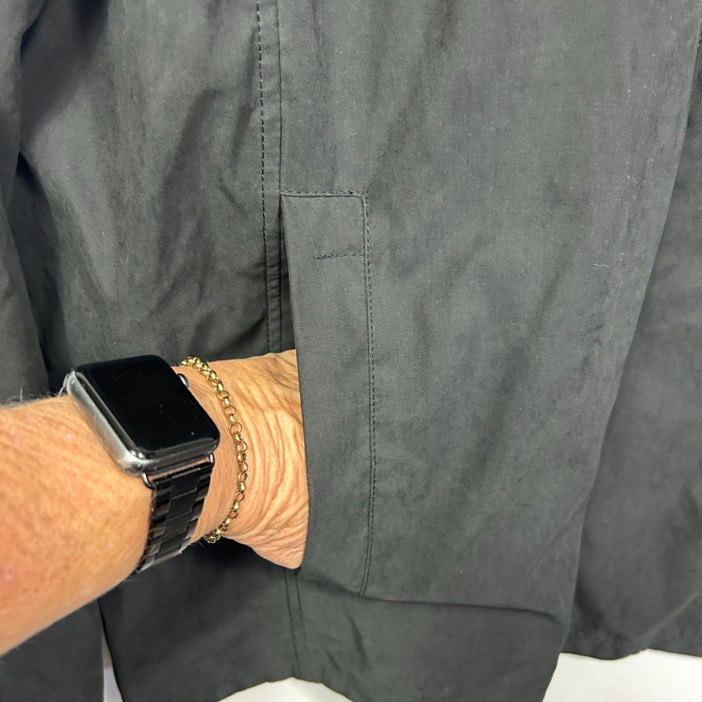 Olive green shirt detail view with smartwatch and bracelets