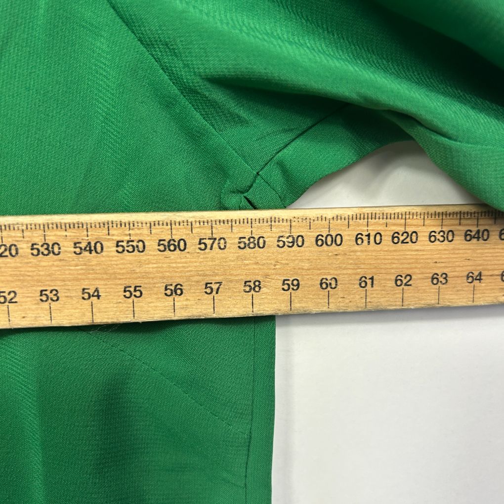 Green garment detail view with measuring tape