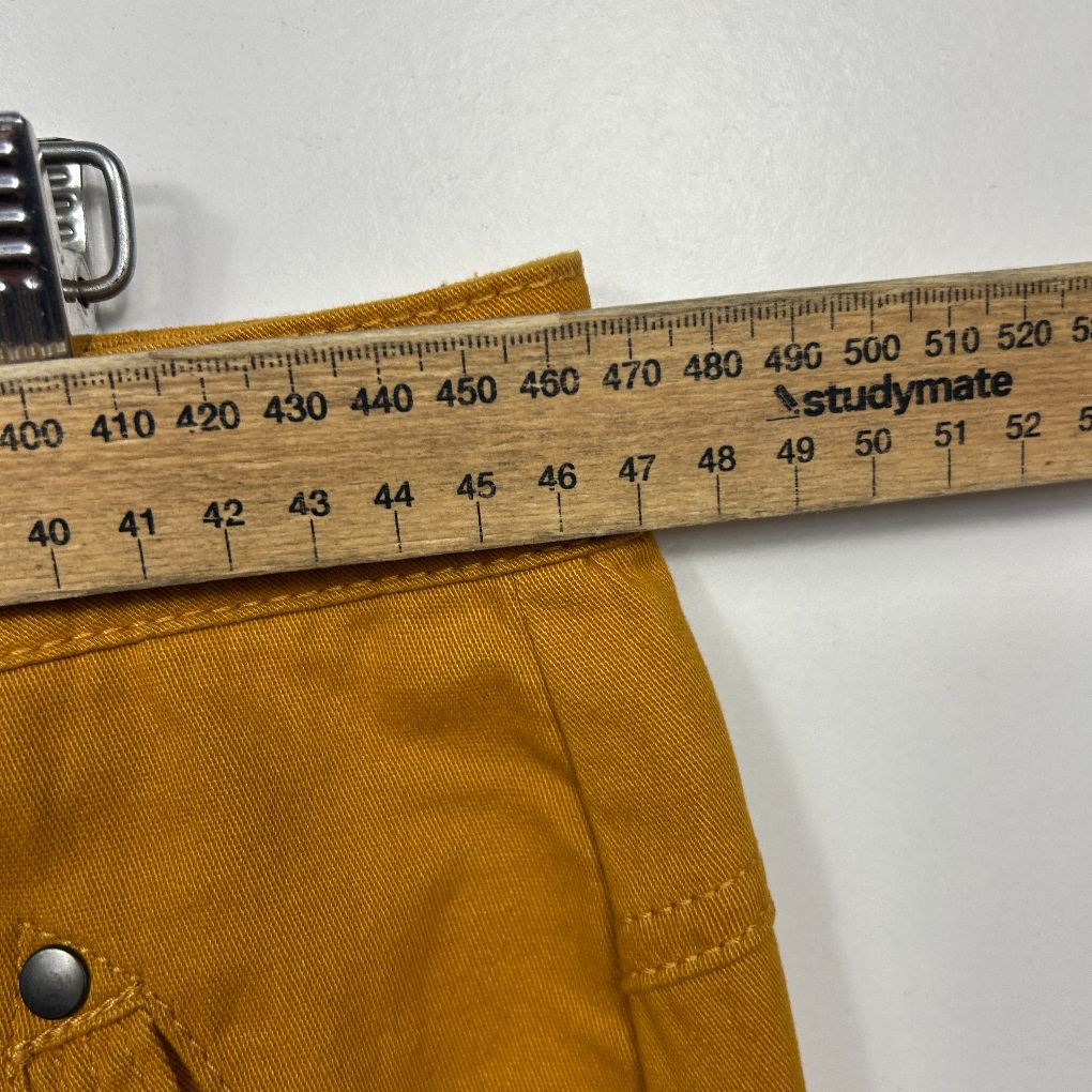 Mustard yellow pants detail view with measuring tape