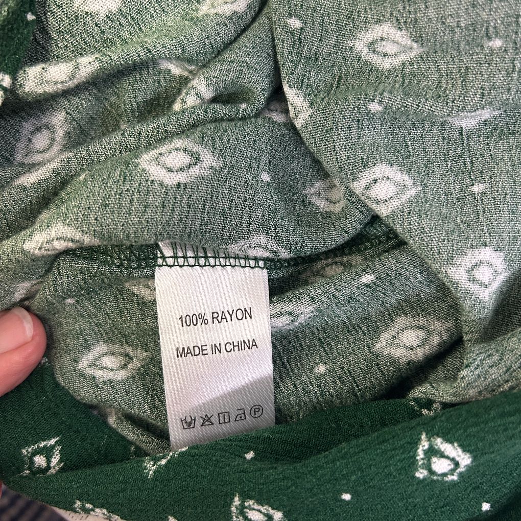 Green knit sweater with white floral pattern label detail view