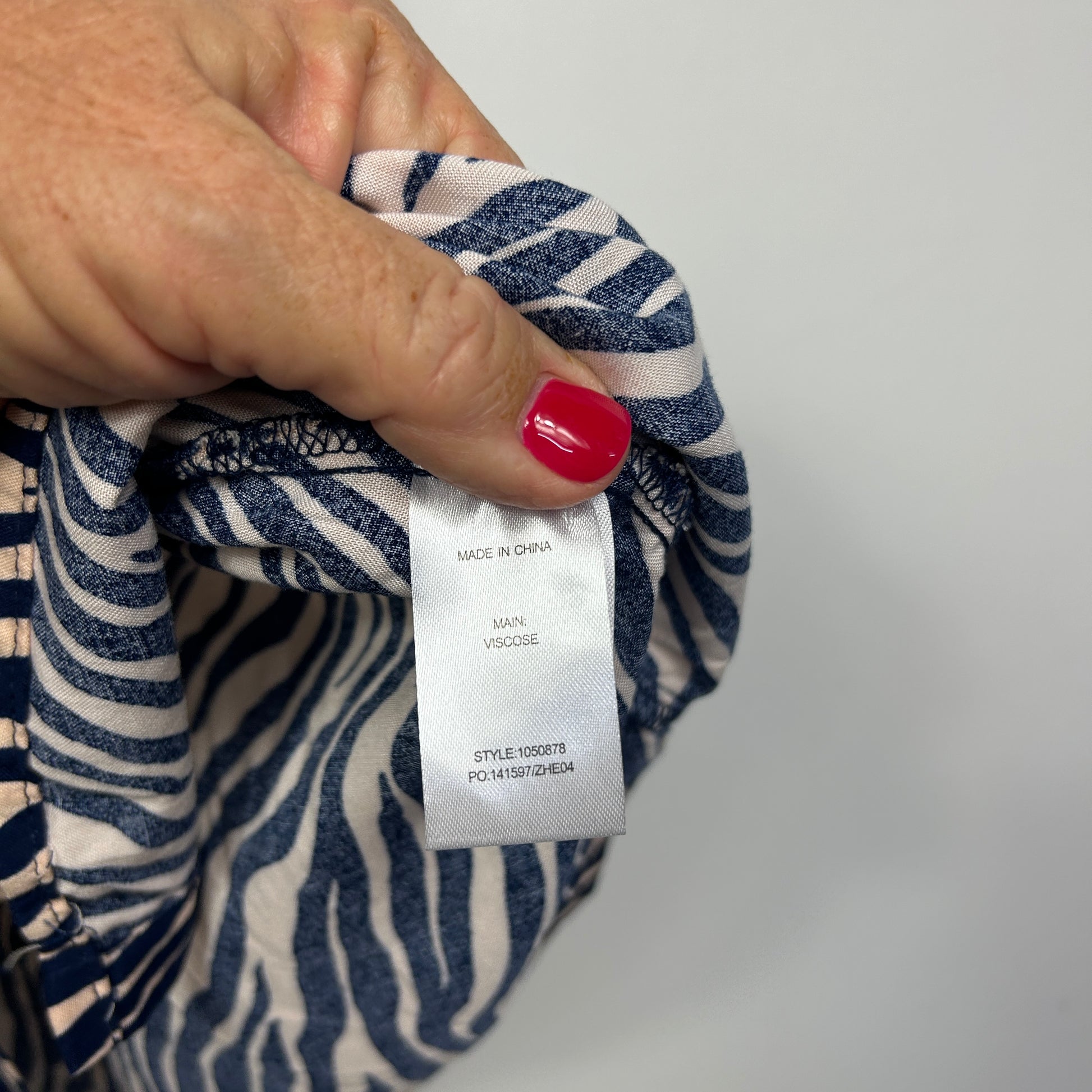 Navy and cream striped top detail view showing label and red nail polish