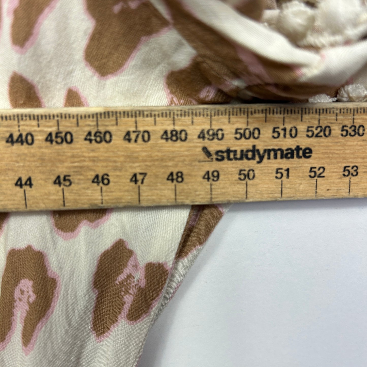 Beige and brown floral print fabric detail view with measurement ruler
