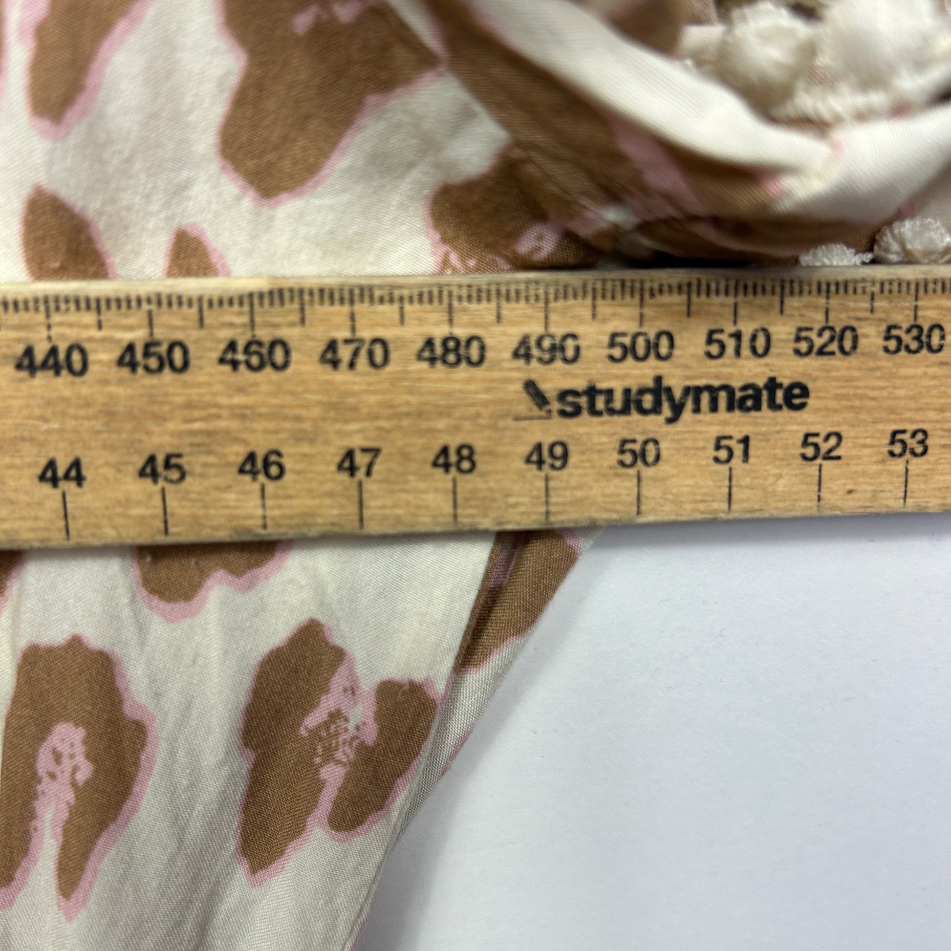 Beige and brown floral print fabric detail view with measurement ruler