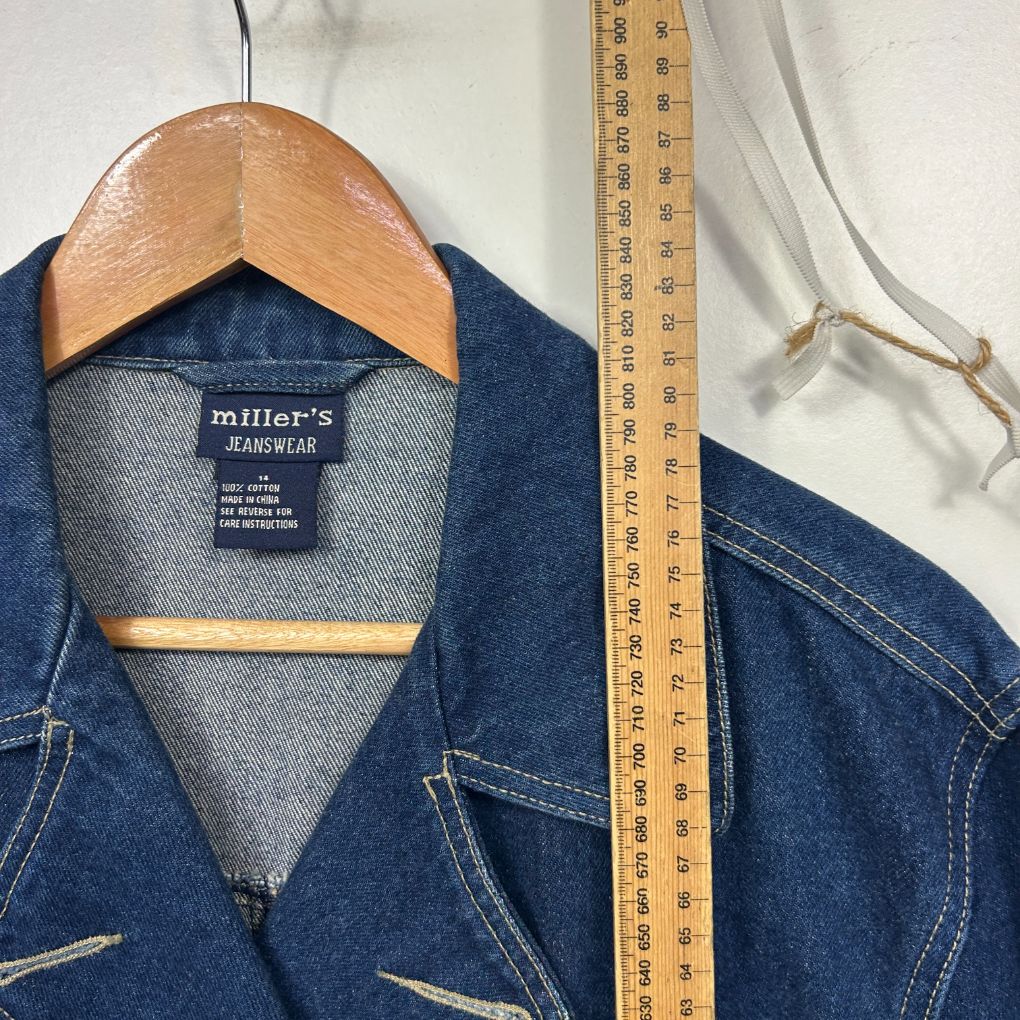 Blue denim shirt front view on wooden hanger with measuring tape