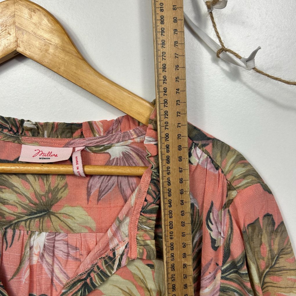 Coral floral shirt front view with wooden hanger and measuring tape