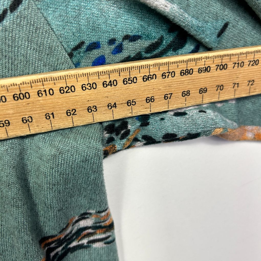 Green knit sweater detail view with measuring tape