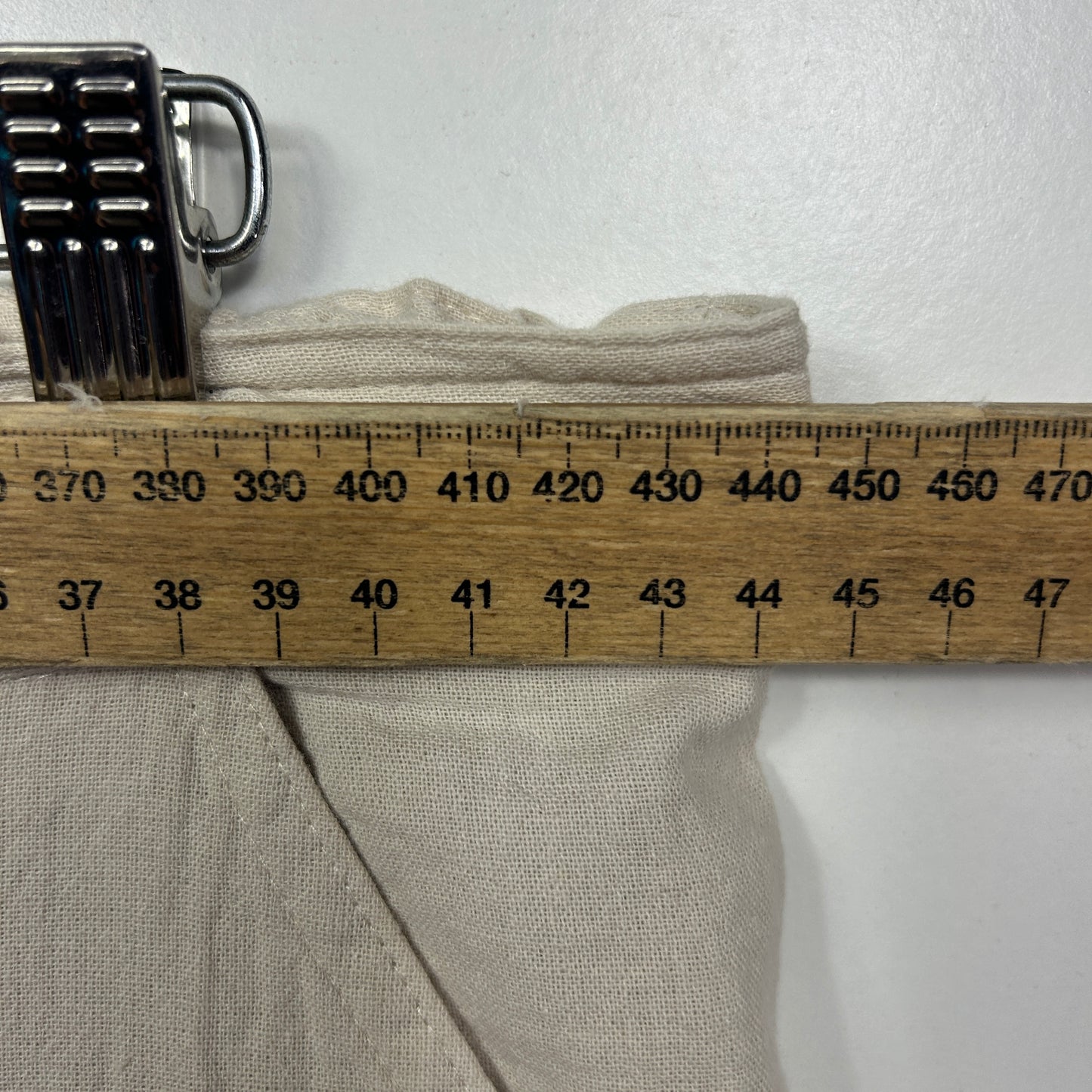 Beige garment detail view with measuring ruler