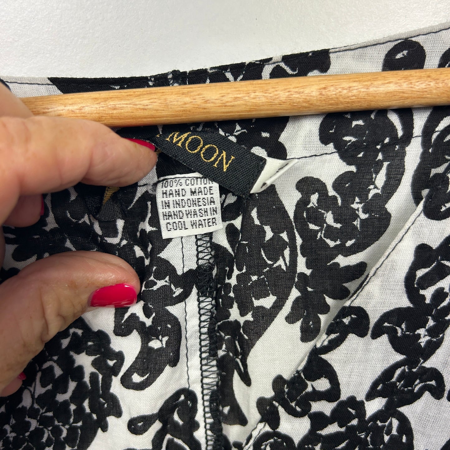 Black and white floral print top detail view with wooden hanger and label