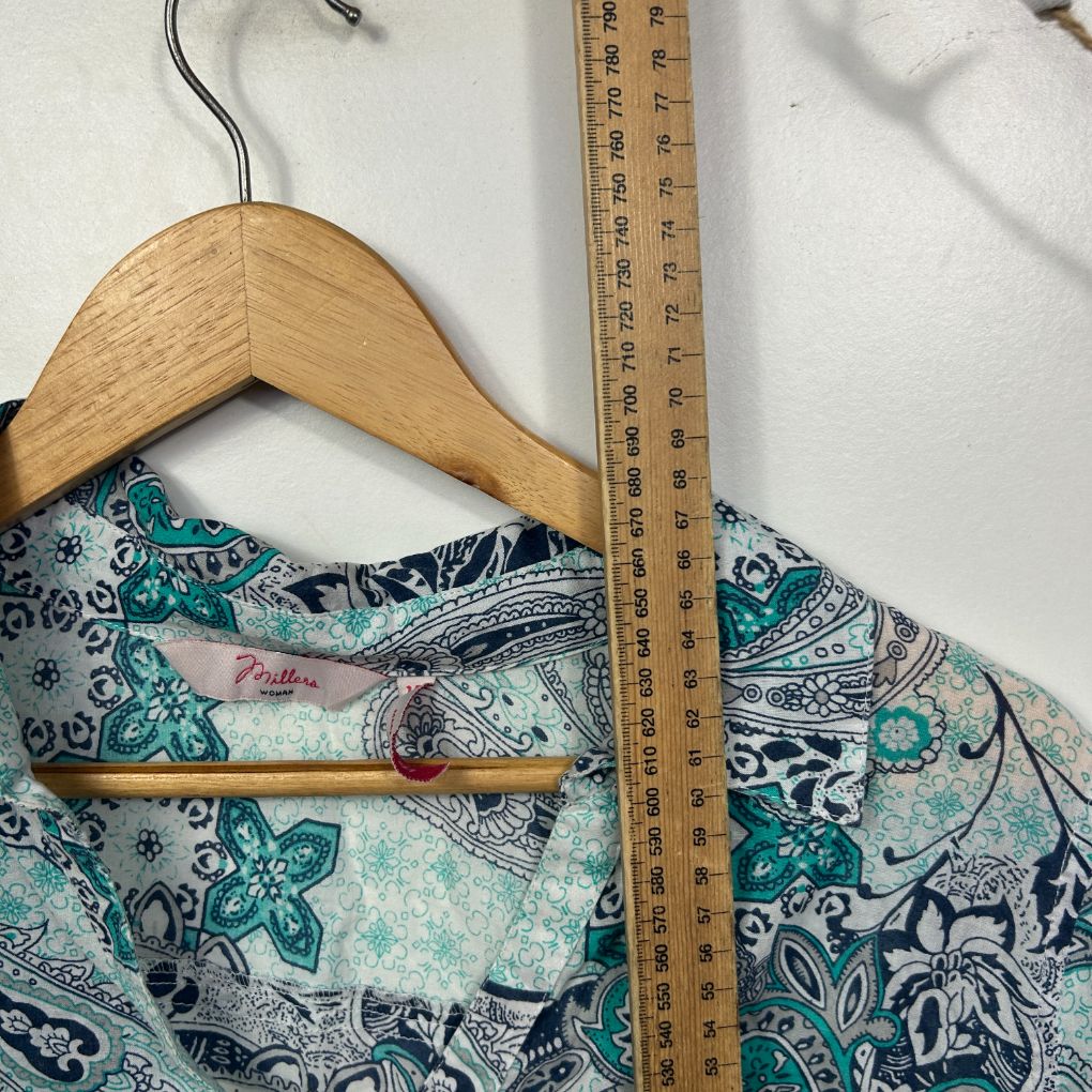 Teal and navy floral top front view on wooden hanger with measuring tape