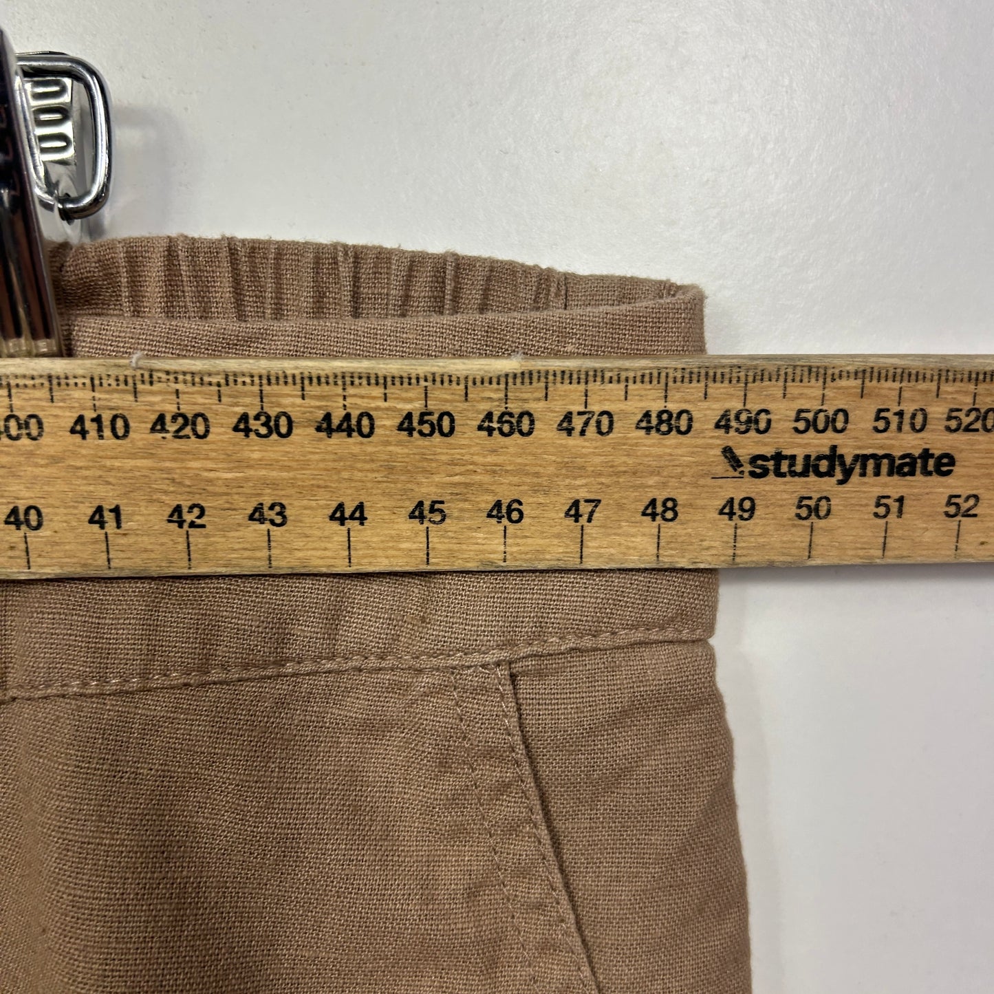 Beige pants waistband detail view with measuring tape