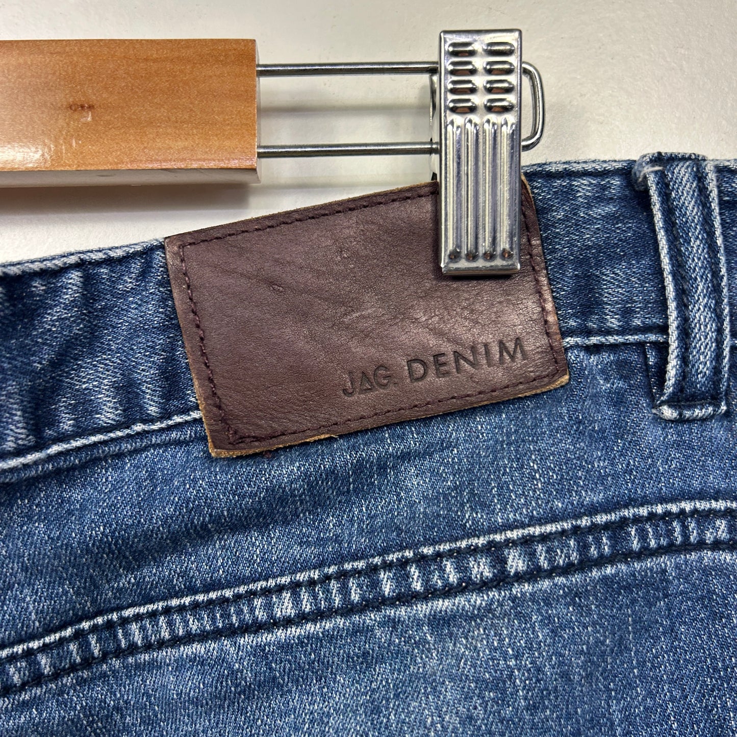 Blue denim jeans detail view with brown leather label