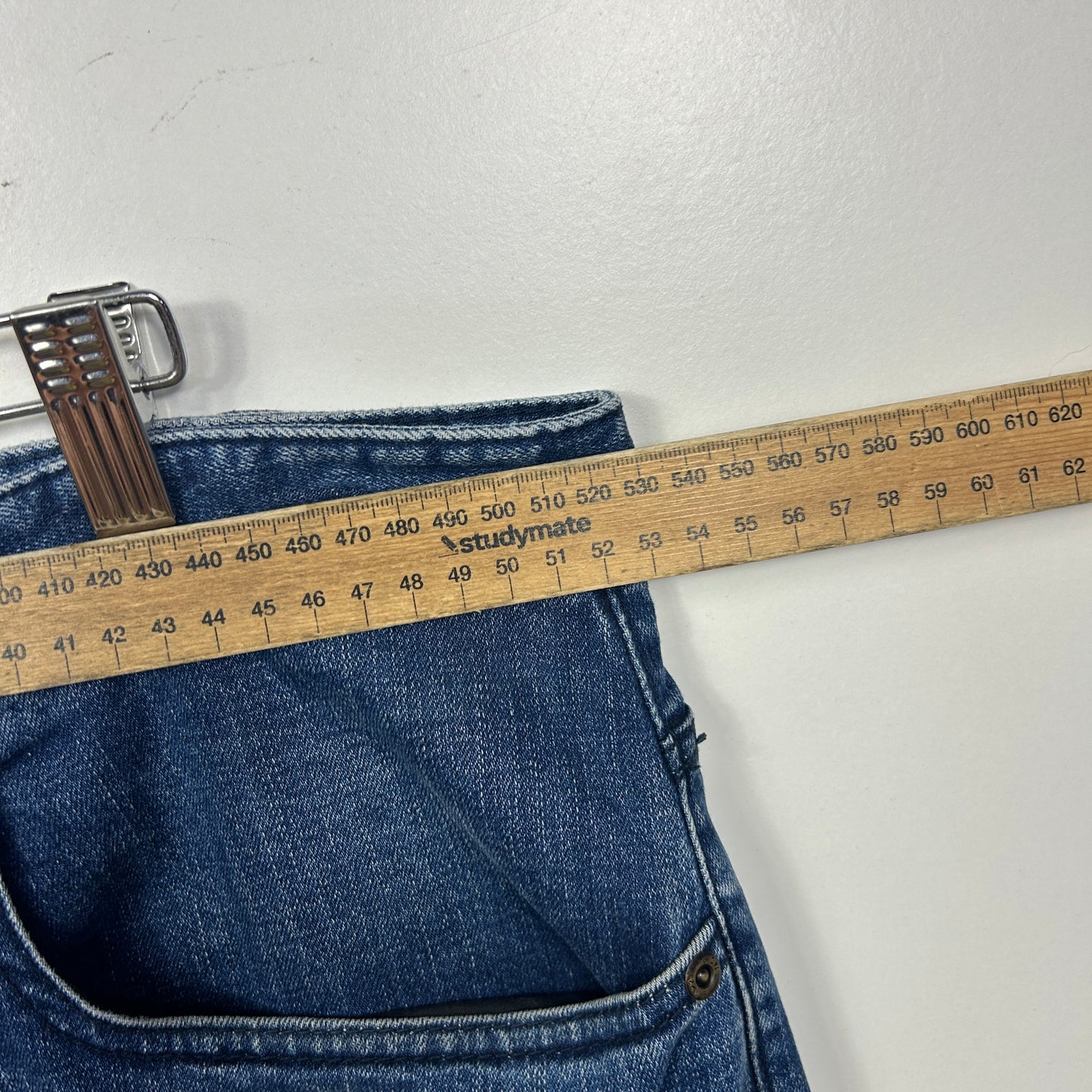 Blue denim jeans with measuring tape detail view
