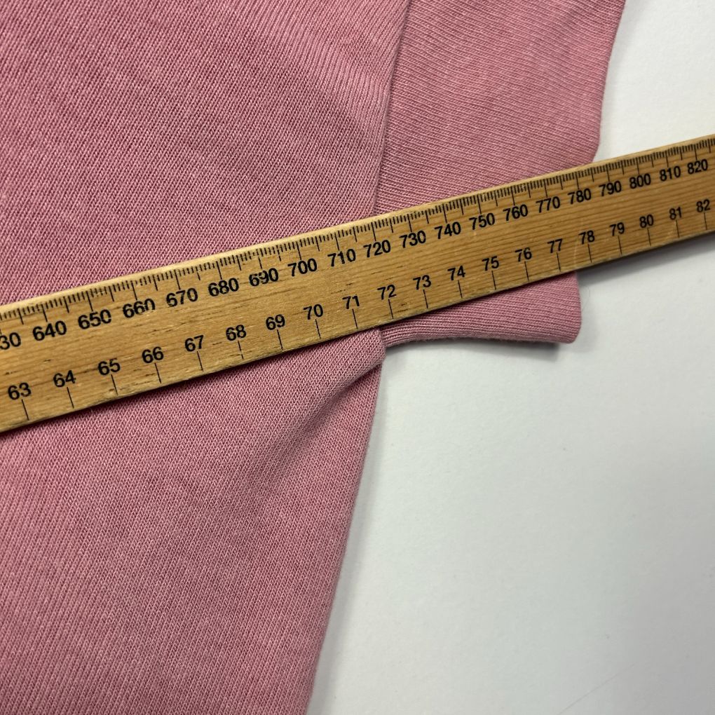 Pink ribbed knit garment detail view with measuring tape