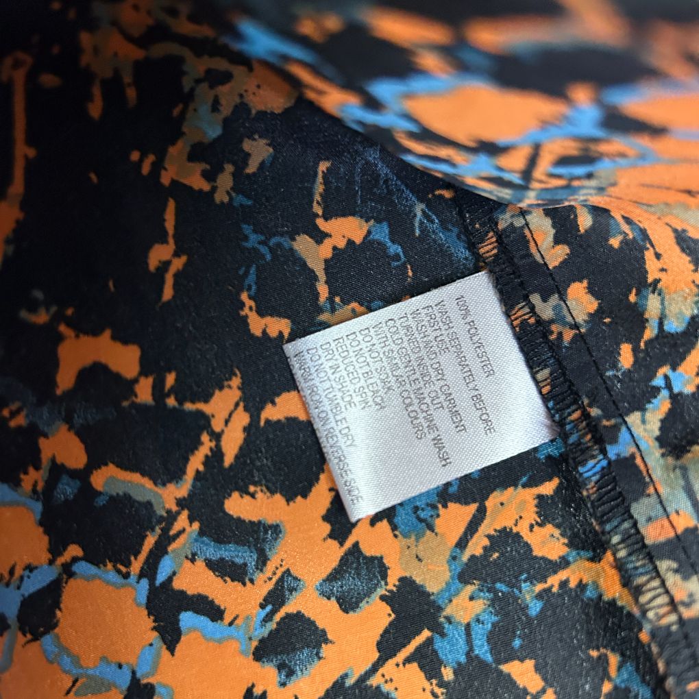 Orange and black patterned fabric detail view with care label