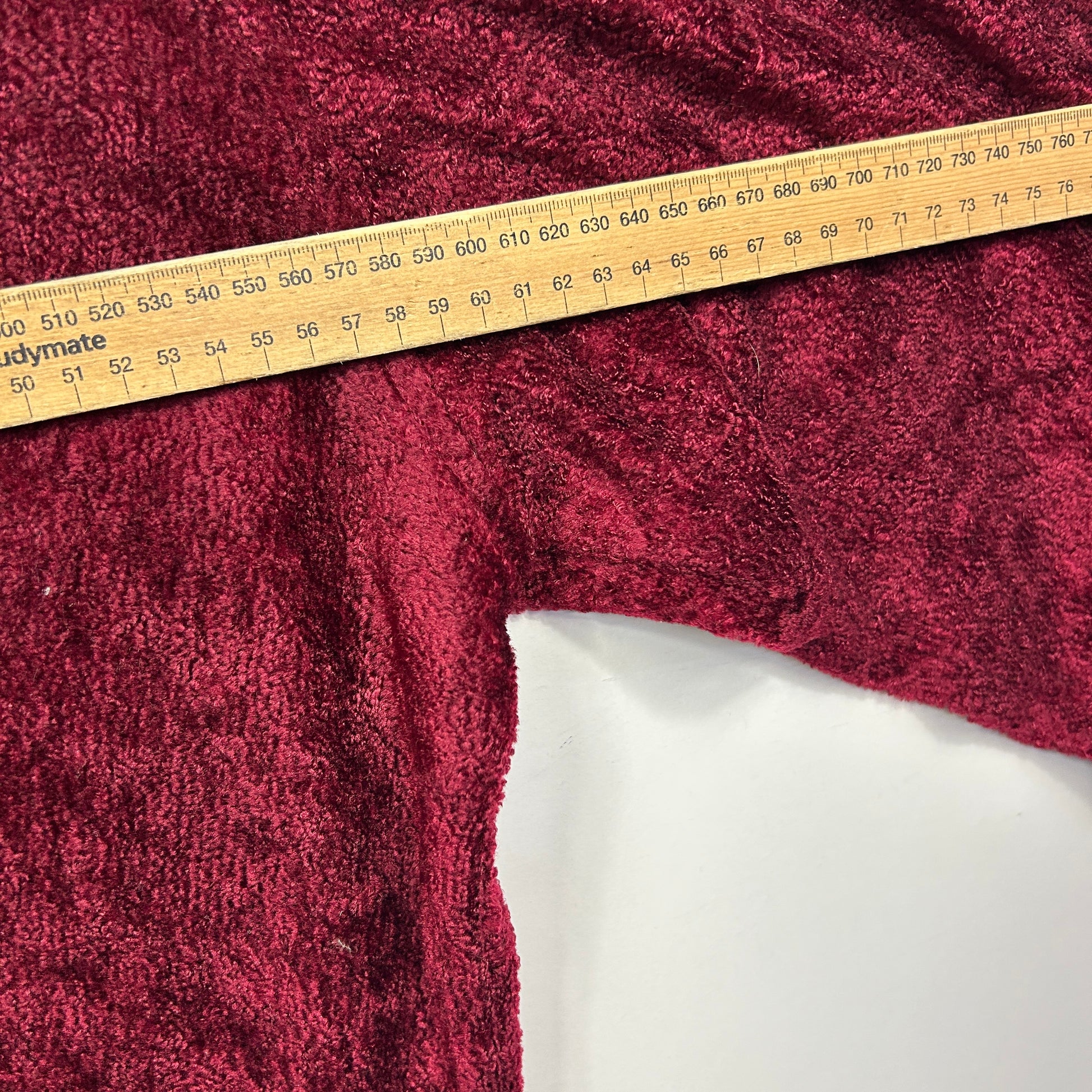 Burgundy knit fabric detail view with measuring tape