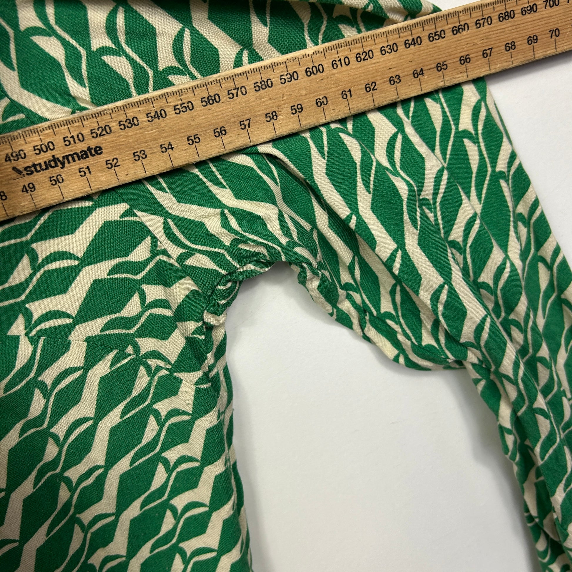 Green and cream leaf print fabric with measuring tape detail view