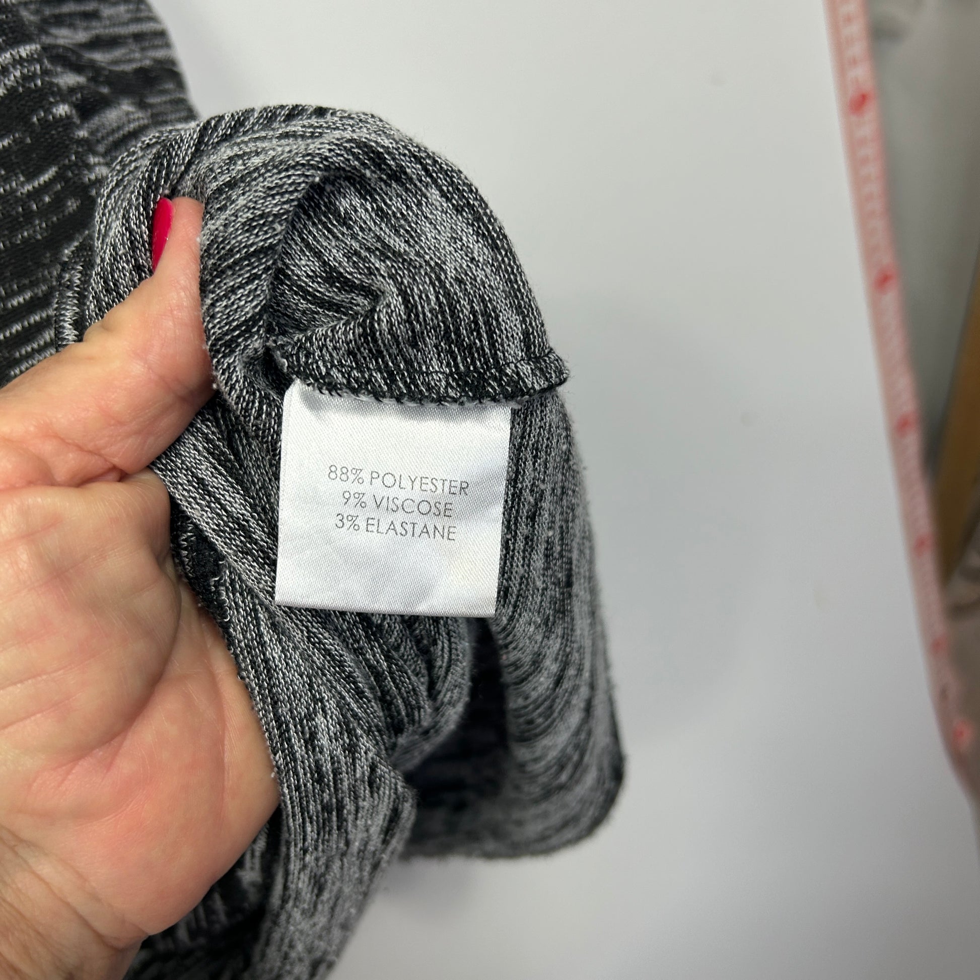 Grey ribbed knit fabric detail view showing care label