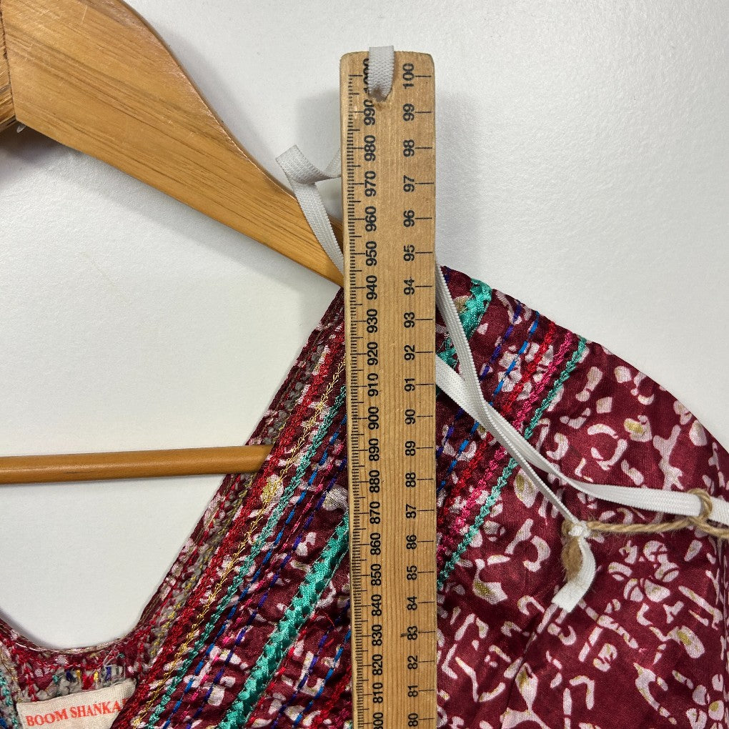 Burgundy floral dress detail view with wooden ruler and hanger