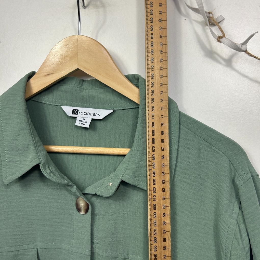 Sage green shirt front view on hanger with measuring tape