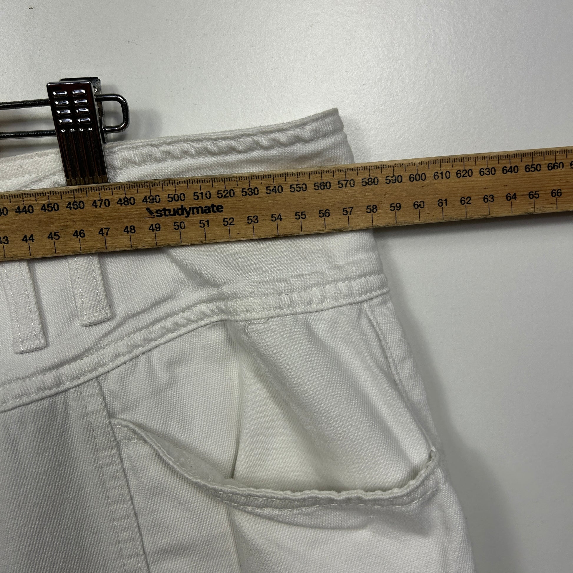 White jeans waistband detail view with measurement tape