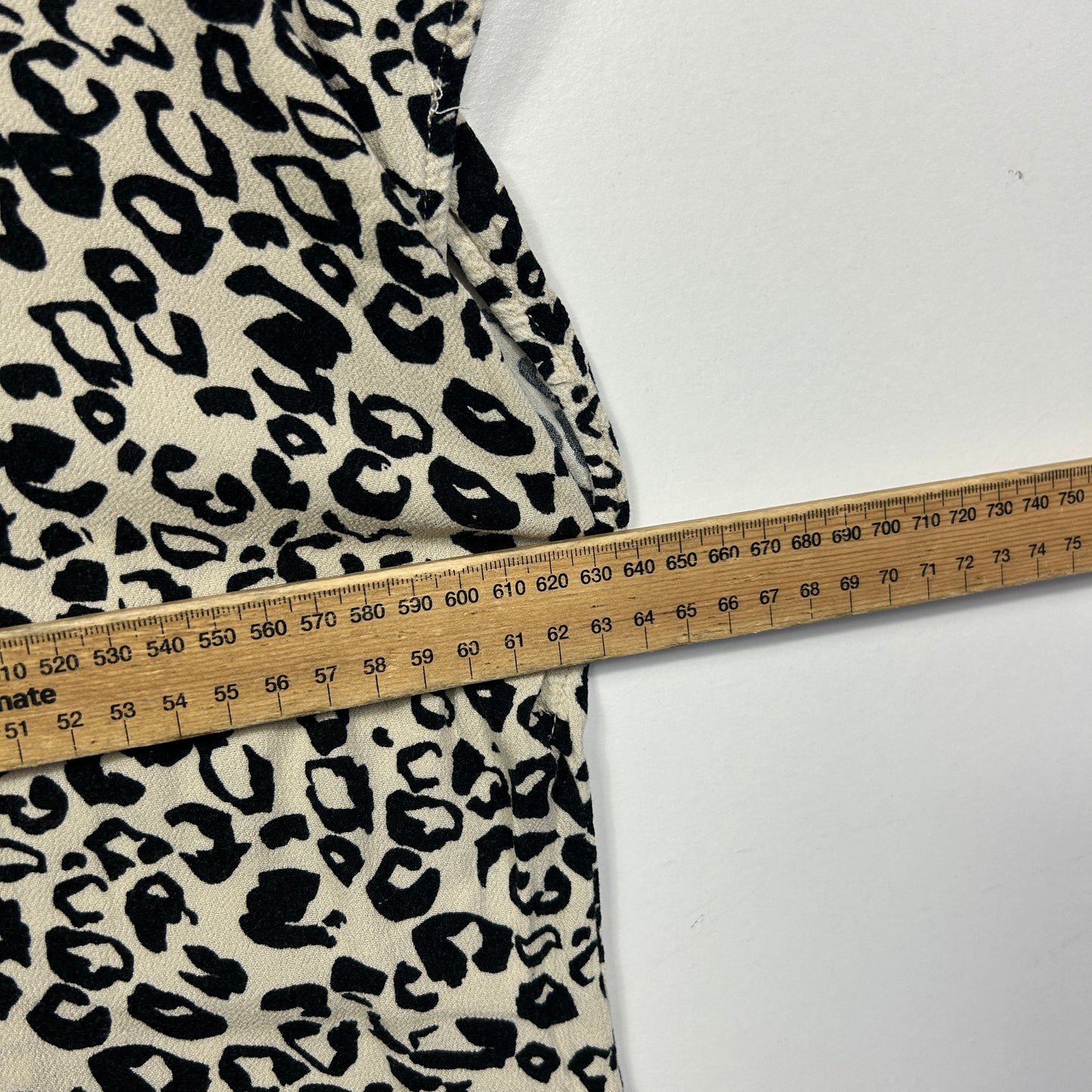 Cream and black leopard print fabric detail view with measuring tape