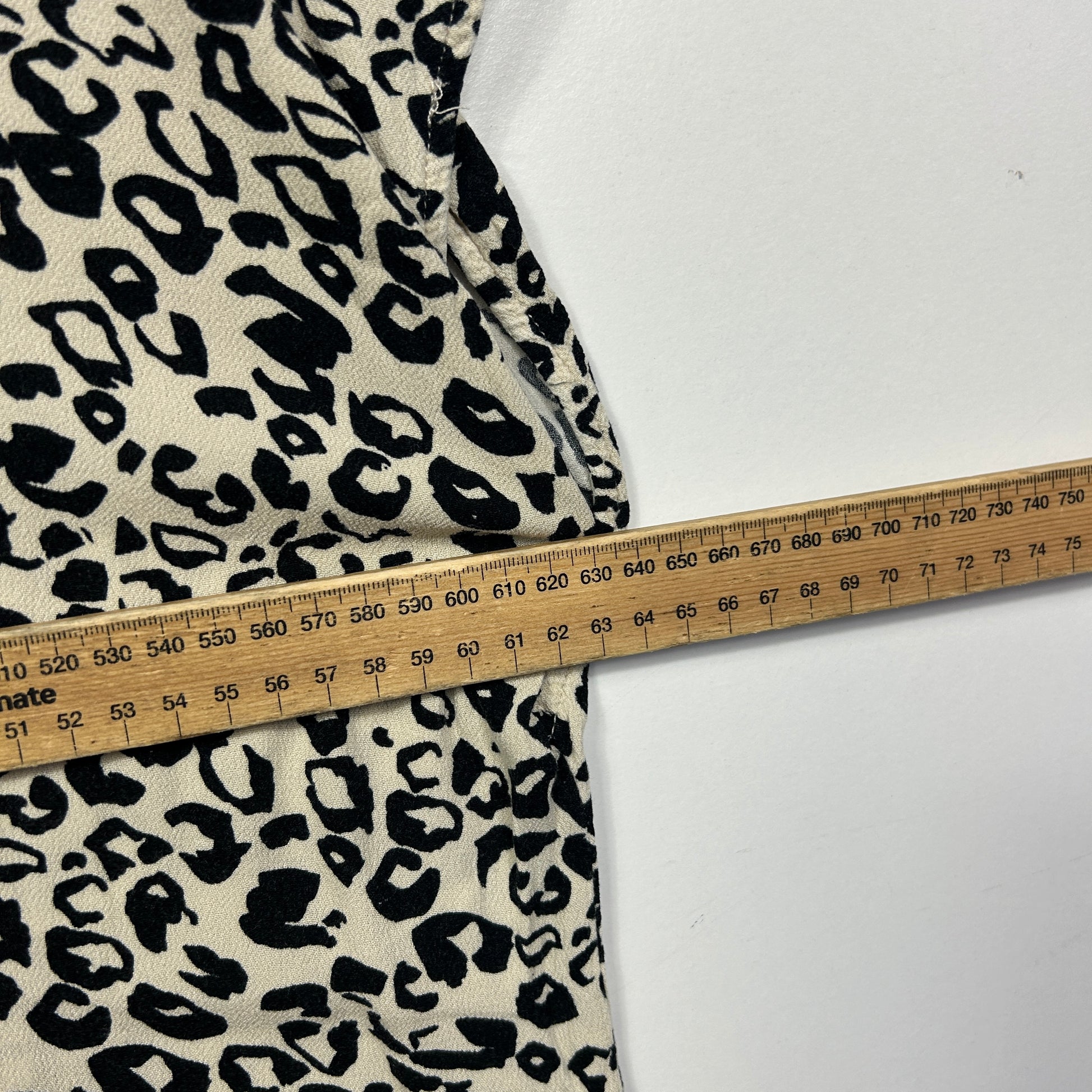 Cream and black leopard print fabric detail view with measuring tape