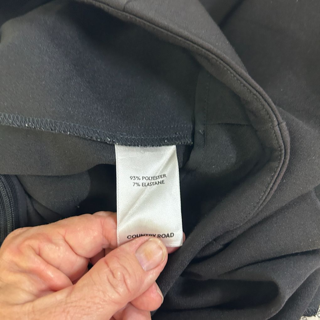 Black garment label detail view showing fabric composition